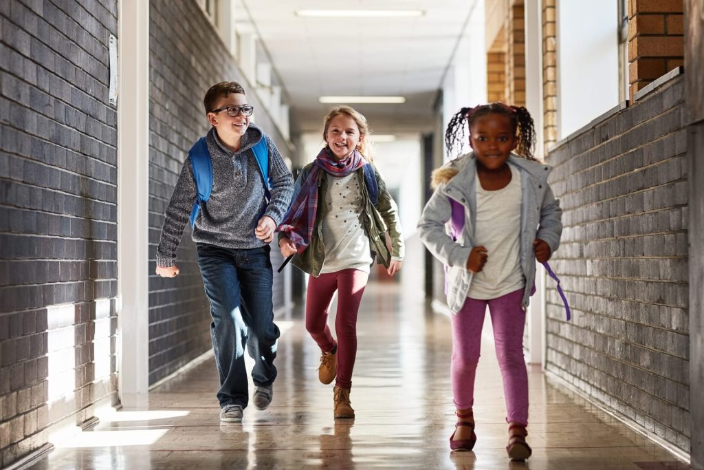 photo - three students running down a pupil referral unit school happily after their school day is finished