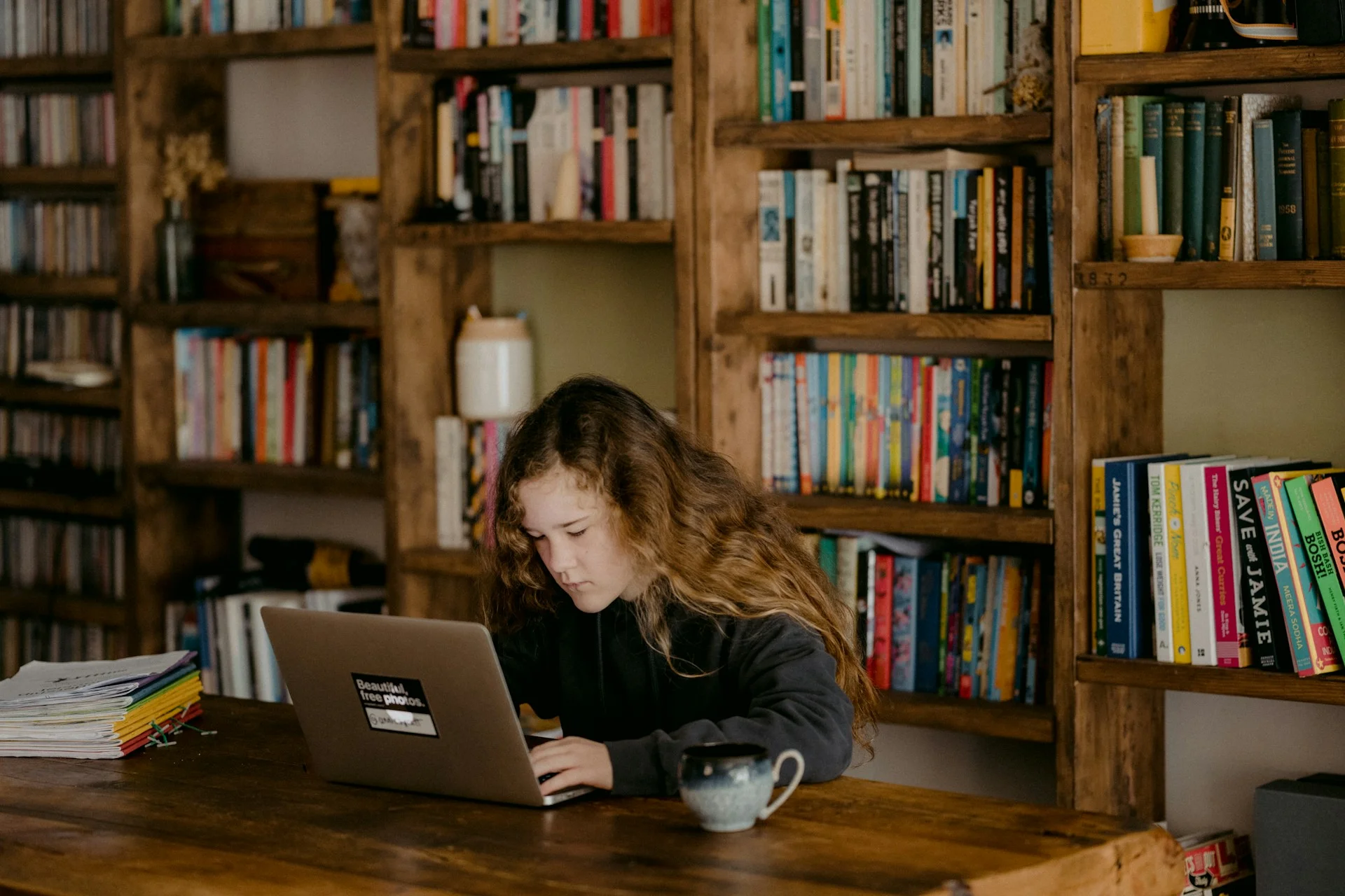 photo - a girl in a library sitting at a desk looking at computer reading about btec level 2 gcse equivalent