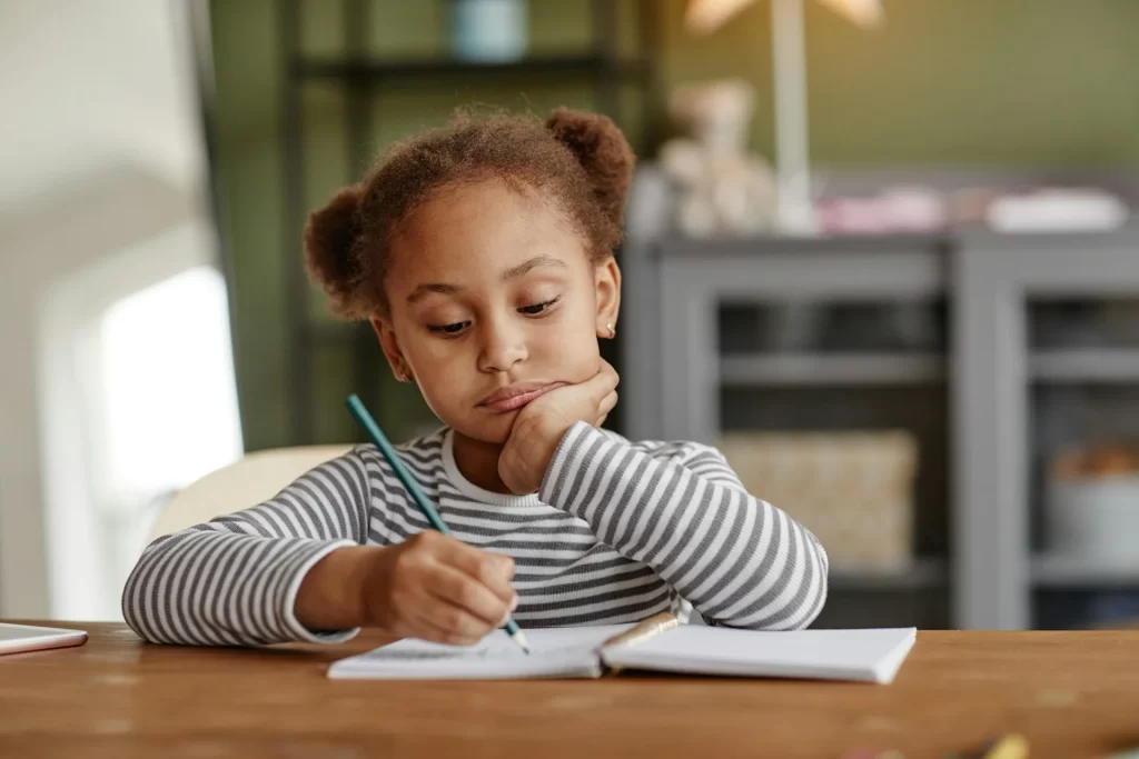 photo - a small girl with ponytails looking at her workbook with SEN or SEND wondering What Does SEND Stand for?