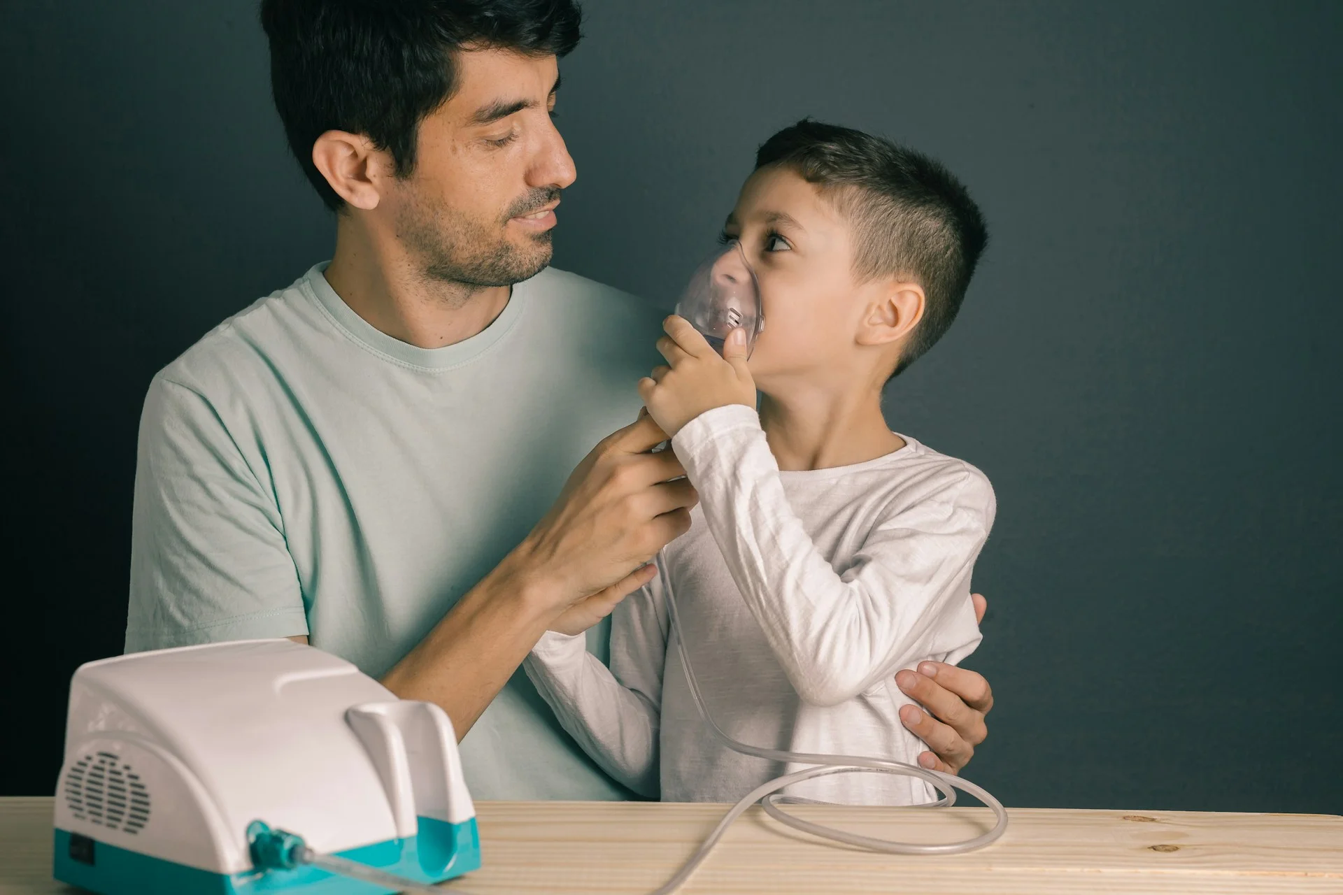 photo - a father and son with a disability looking at each other while the son uses assistive apparatus covered by ehcp funding