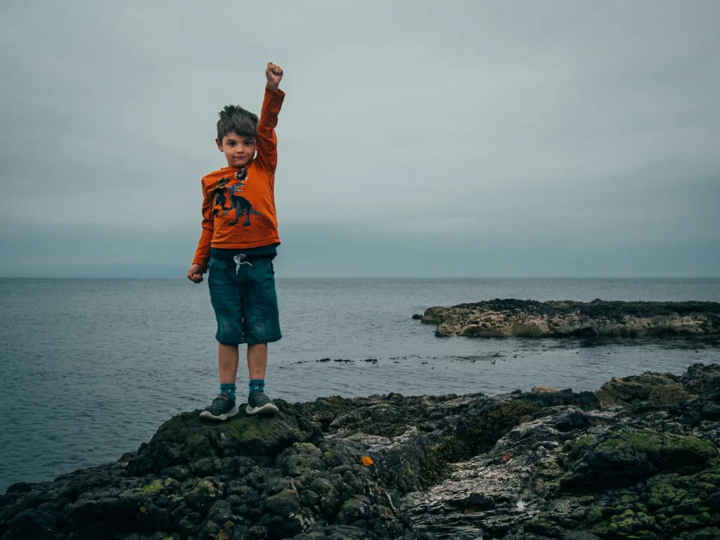 photo - a boy standing on a shore with a beautiful gloomy view behind him, cheering for hertfordshire children's services 