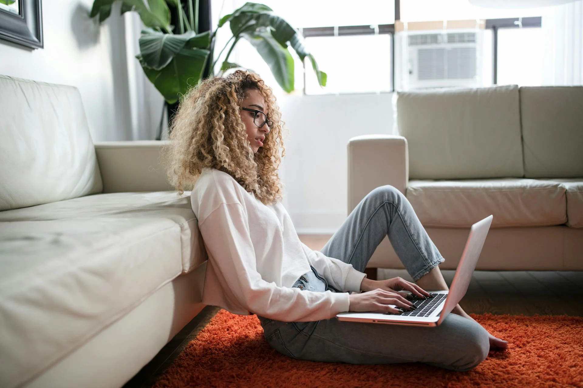 photo - a sad woman sitting on the floor with her laptop on her leg checking the checklist dyspraxia symptoms