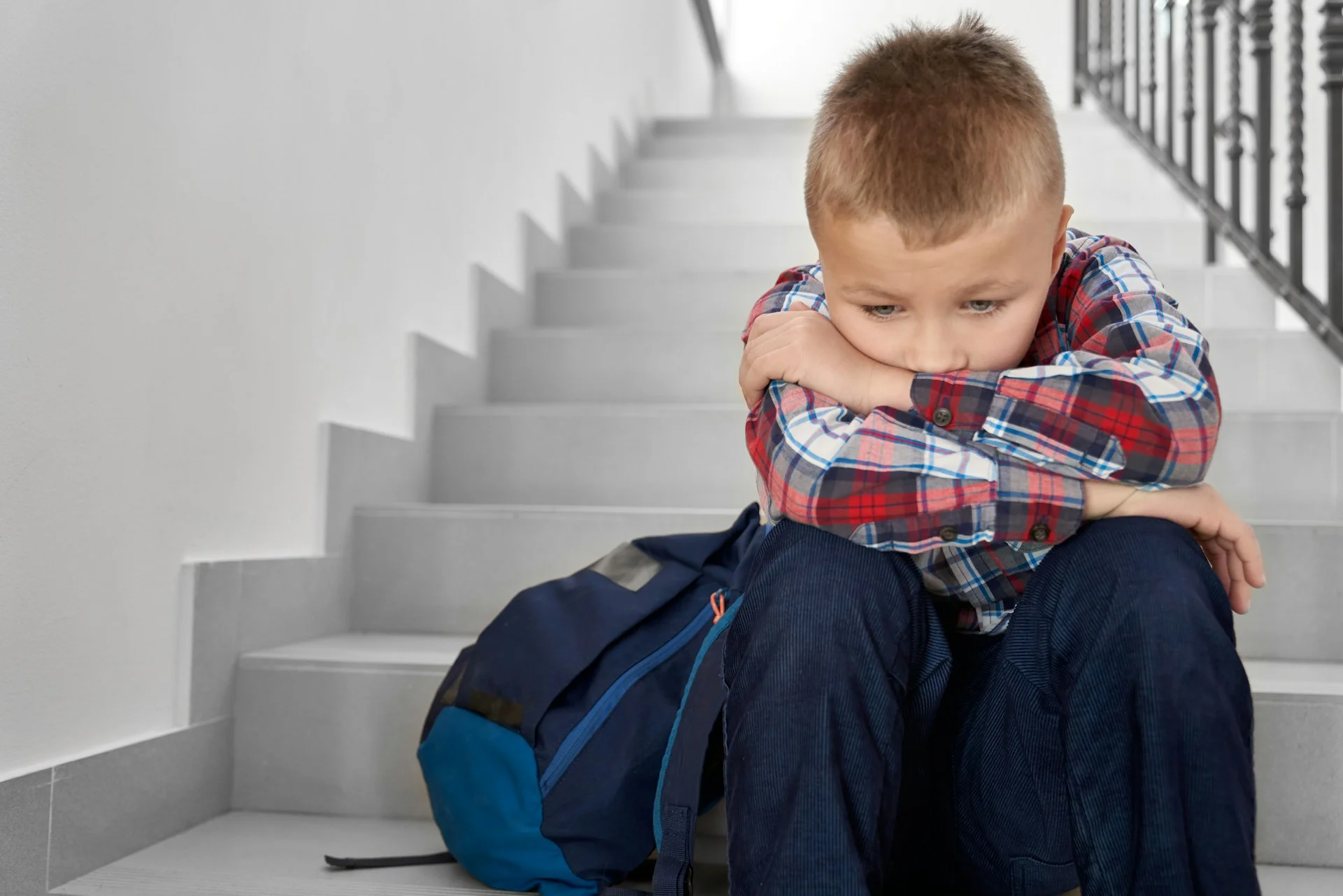 photo - a boy with moderate learning difficulties is sitting alone on the staircase in his school