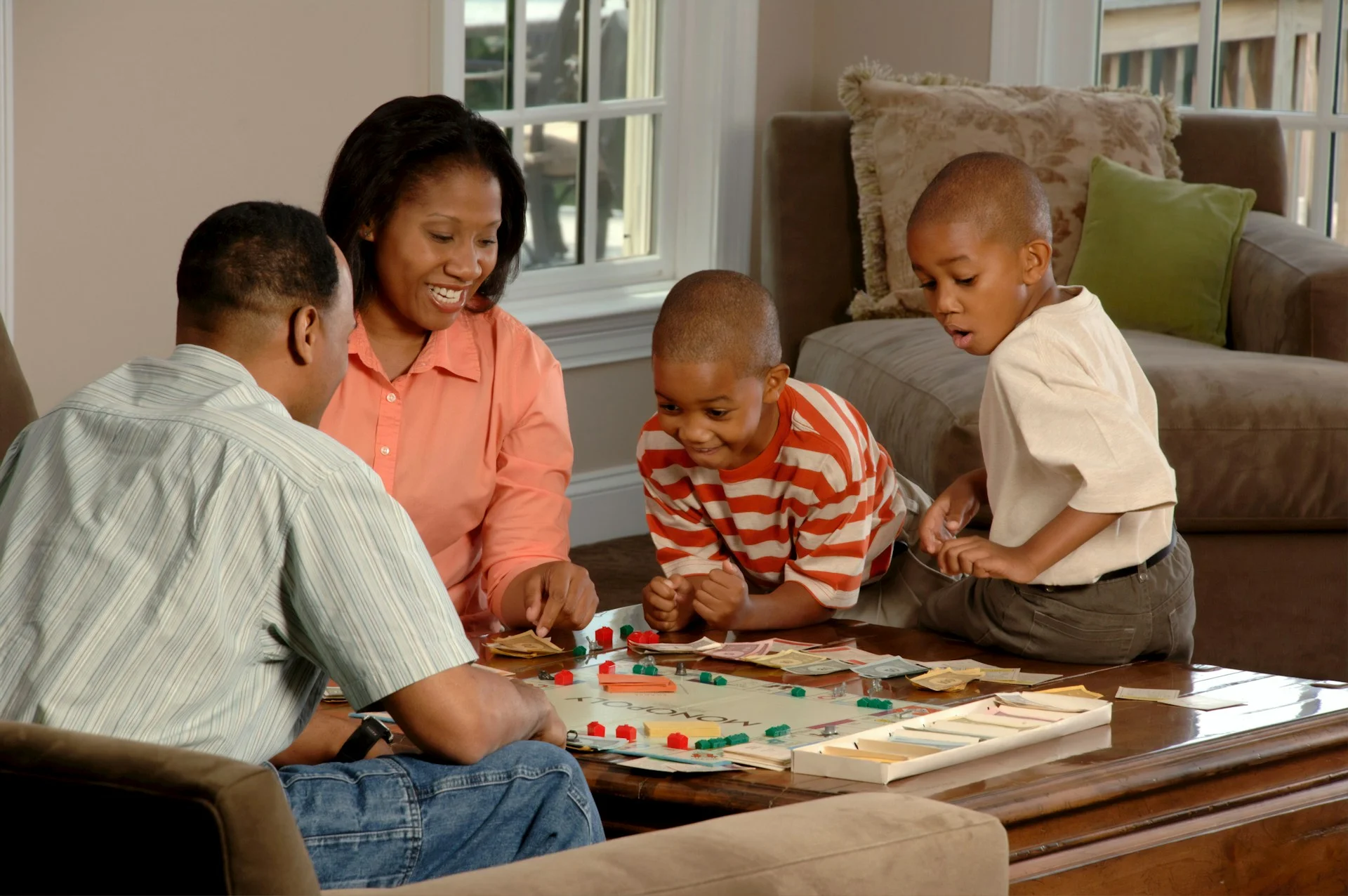 photo - a family of two children, a mother and a father are sitting at dinner table playing a board game to boost the children's emotional literacy