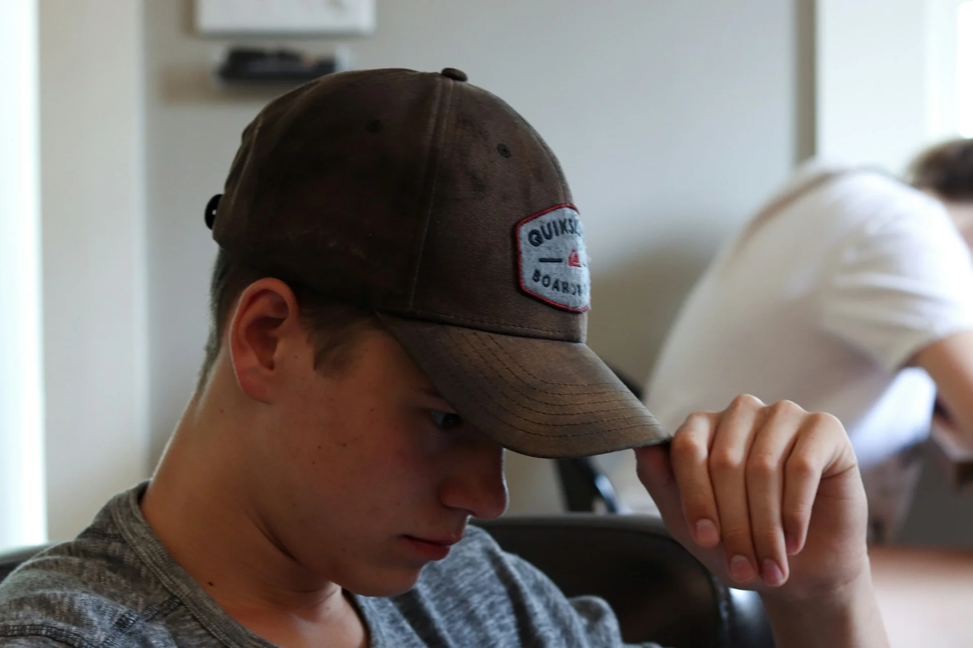 photo - a teenager with arfid and autism looking down in a cap