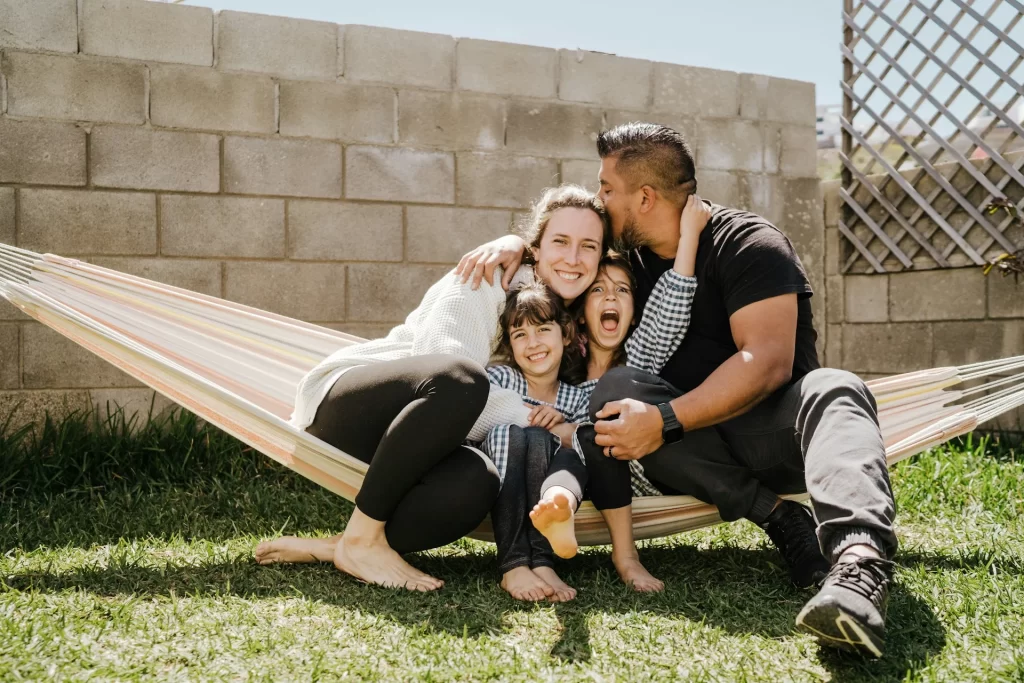 photo - two sen parents with their two children on a hammock enjoying a summer day outside