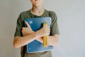 photo - a boy with one of the sen types holding pencils and a textbook 