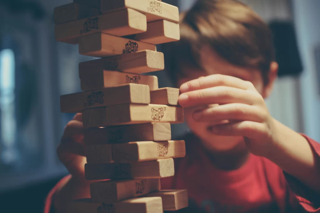 Photo - A boy is playing the building block game Jenga portraying creative activities for children.