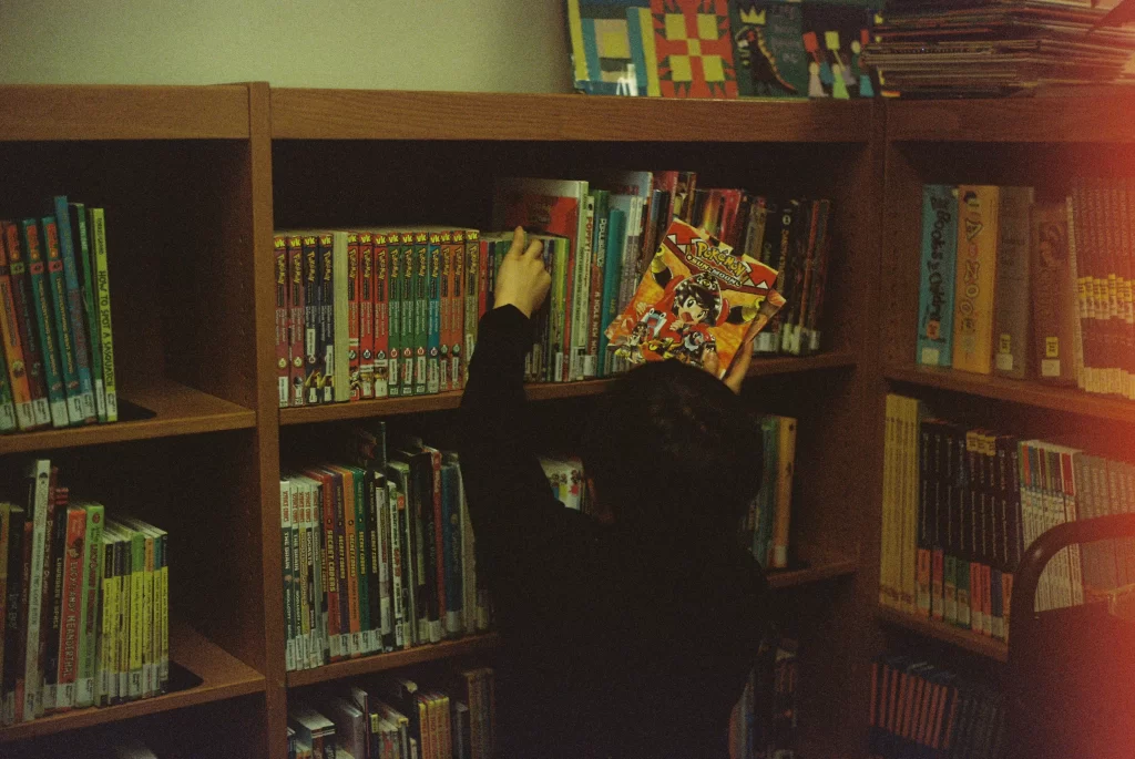 Photo - Boy looking for books on a bookshelf showing dyslexia support in schools. 