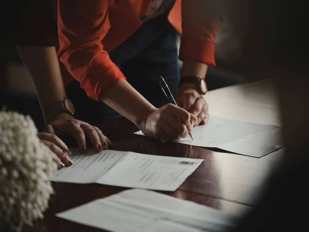 Photo - Close-up of people signing documents illustrating the process of completing an appeal EHCP or SEND tribunal forms.