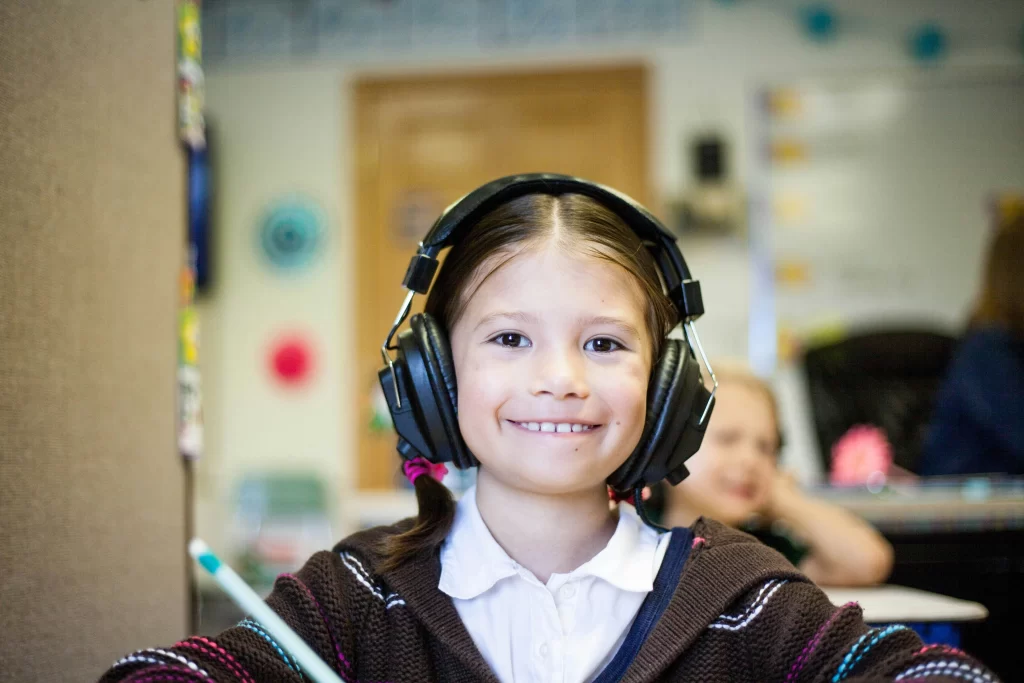 Photo - Girl smiling with headphones on using dyslexia support in schools.