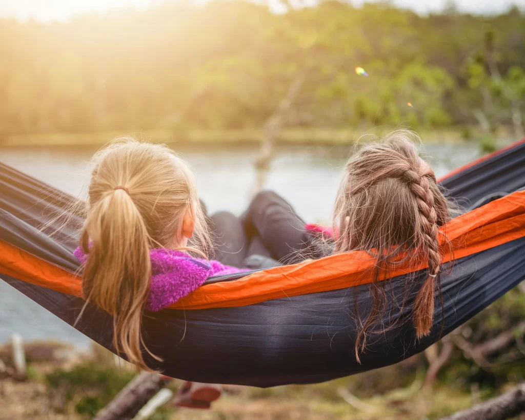 Photo - girls on hammock by lake participating in SEN activities from SEN classroom ideas