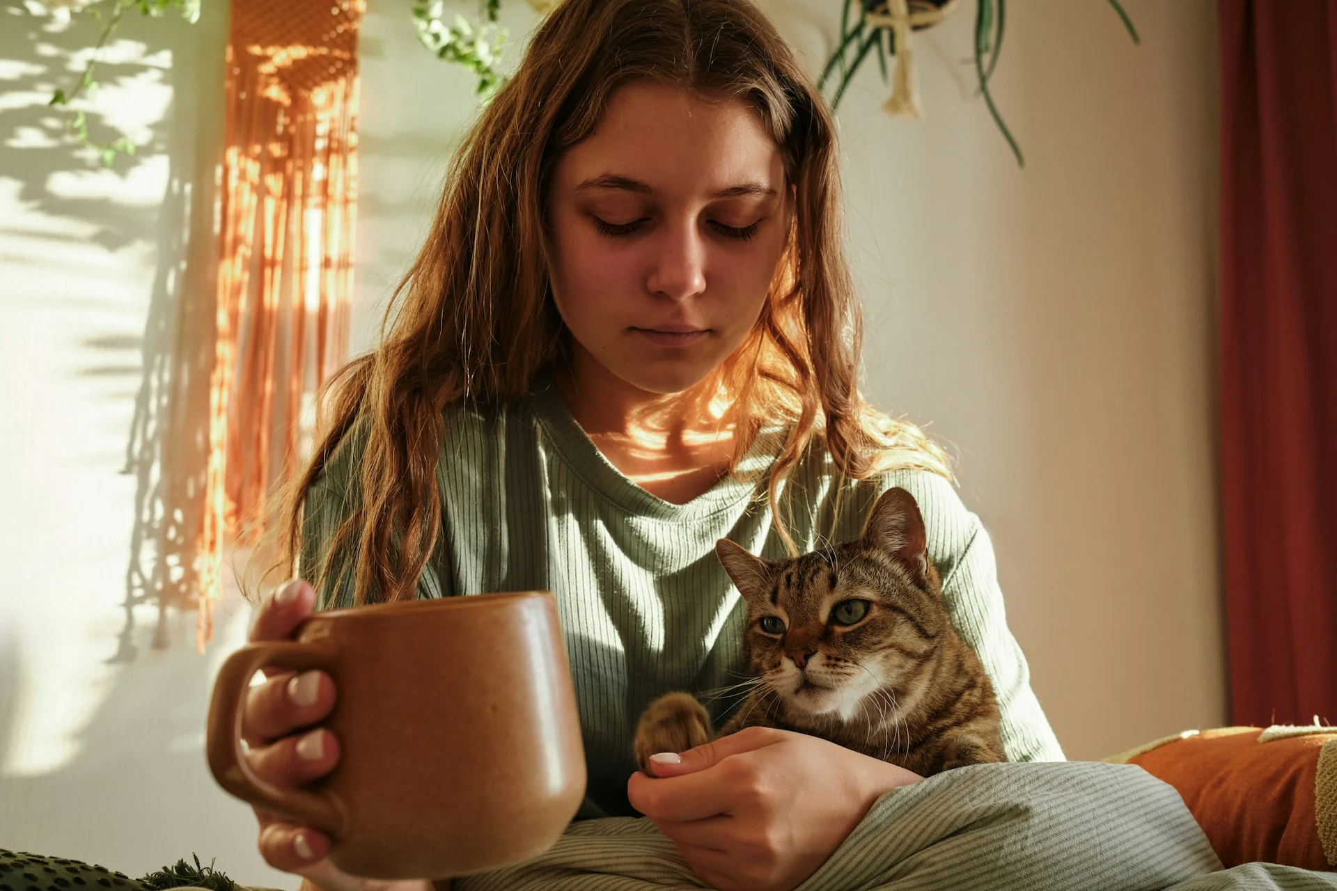 photo - a girl struggling with social emotional and mental health at home with a cup of tea and her cat 