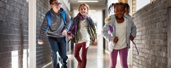 photo - three students running down a pupil referral unit school happily after their school day is finished