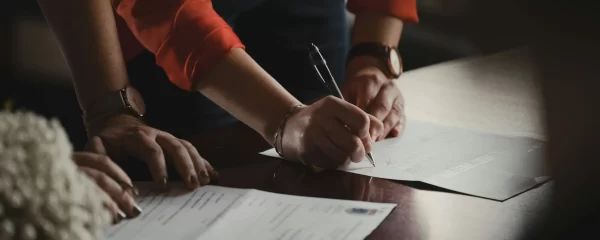 Photo - Close-up of people signing documents illustrating the process of completing an appeal EHCP or SEND tribunal forms.