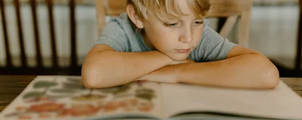 photo - a boy with arfid and autism reading a book in his living room