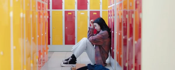 photo - a girld with bad gcse grades sitting on the floor of a locker room upset