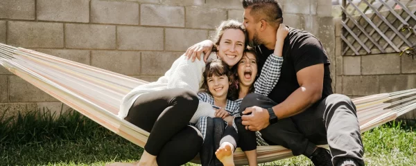 photo - two sen parents with their two children on a hammock enjoying a summer day outside