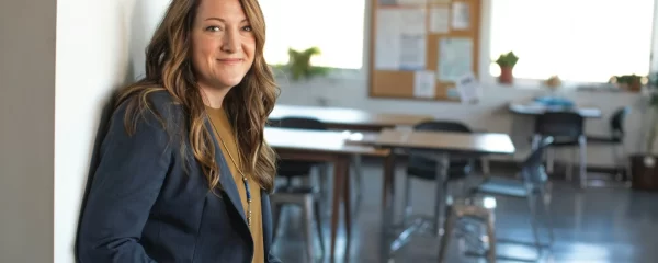 photo - a special educational needs teacher smiling at the camera wearing formal clothes in an alternative provision schools classroom